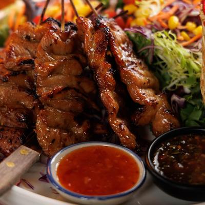 Close up of a plate with Thai grilled pork skewers.