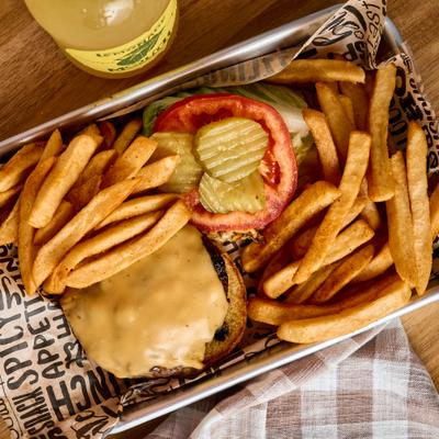 Cheeseburger with lettuce, tomato, and pickles, served with french fries.
