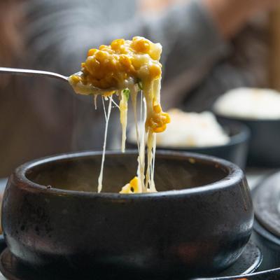A spoonful of corn cheese soup, above the bowl.