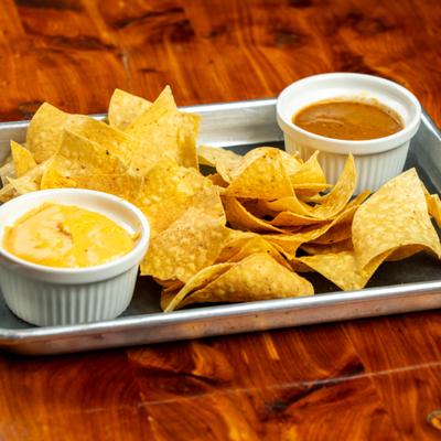 Chips with salsa and cheese dip, served on a tray.