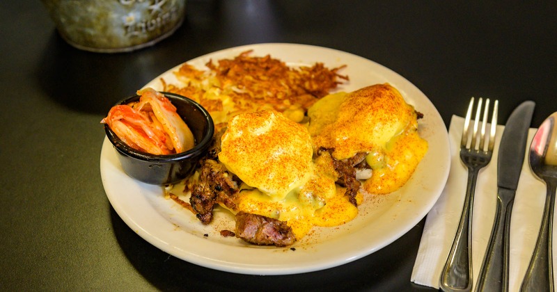 Eggs Benedict with steak, hash browns, and pickled vegetables