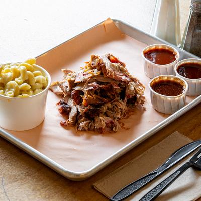 Pulled pork served with a side of hatch mac and cheese and BBQ sauces.