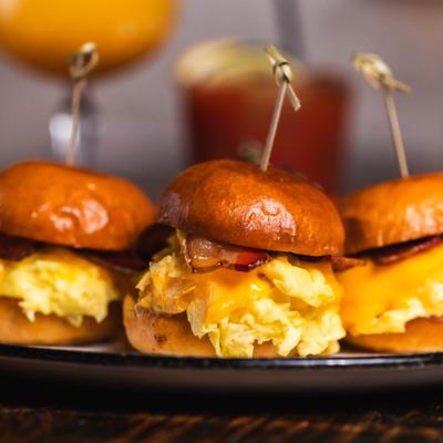 Close-up of breakfast sliders with scrambled eggs and bacon on mini brioche buns.