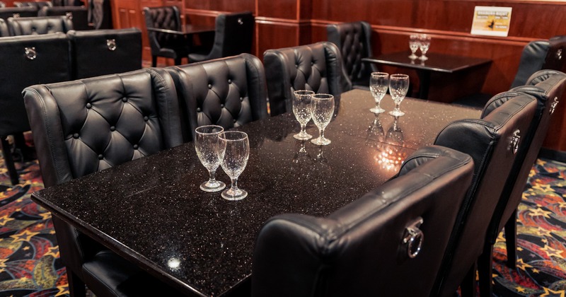 Interior, black tables with glasses and button tufted black chairs