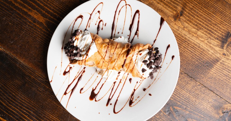 Cannoli with chocolate chips served on a plate with chocolate drizzle