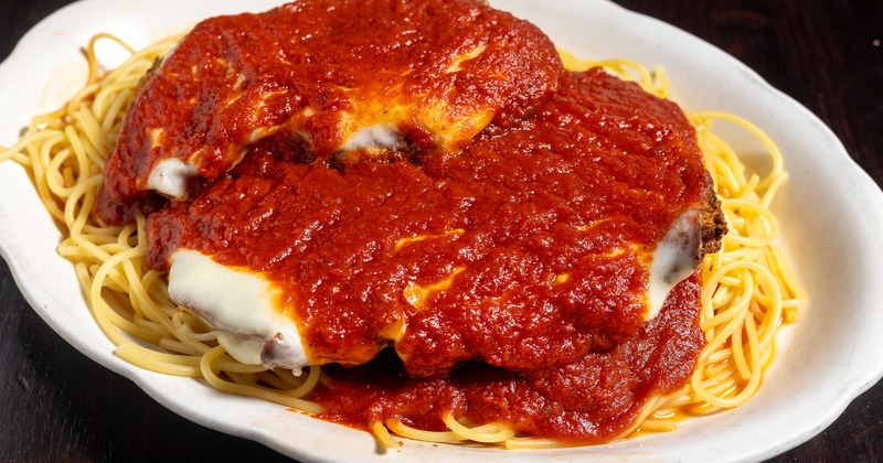 Chicken parmesan over spaghetti with tomato sauce
