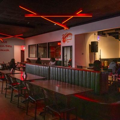 Interior featuring red neon lights, booths, and tables.