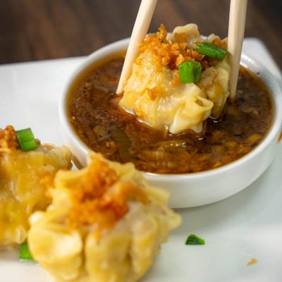 Dumplings served with dipping sauce in a small bowl.