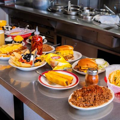 Assorted dishes on a counter with condiments and a bag of potato chips.