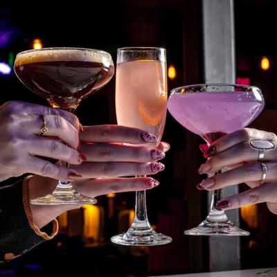 Three hands holding different cocktails.
