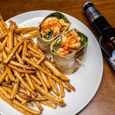 Buffalo chicken wrap served with fries and a bottle of beer.