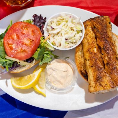 Broiled Cajun Mahi Sandwich on a bun, with mayo, lettuce, tomato, slaw