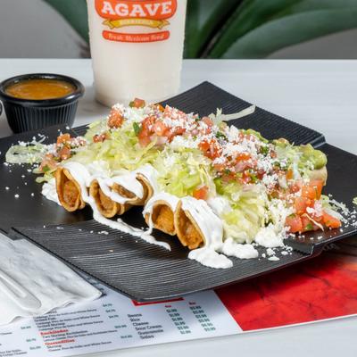Flautas, topped with sour cream, guacamole, cheese, and salsa.