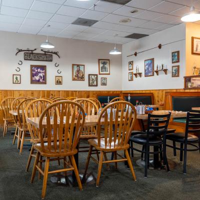 Interior with wooden paneling, wooden chairs, and framed pictures on the wall.