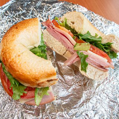 Bagel sandwich filled with ham, Swiss cheese, and vegetables.