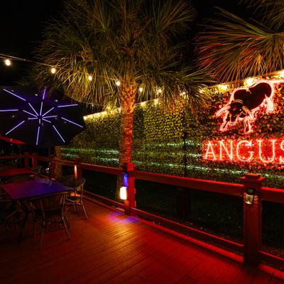 Patio with tables, chairs and restaurant's neon sign.