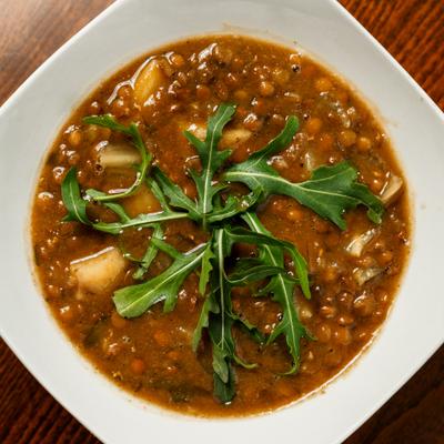 Lentil soup topped with arugula, overhead view.