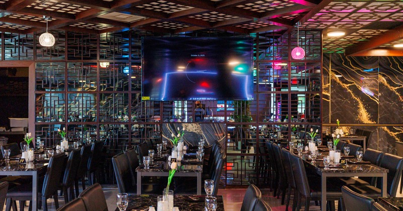 Interior, marble tables, black chairs, ornate wall panels, and a large TV screen