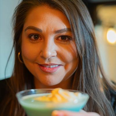 A person smiling and holding a glass of Pistachio Martini.