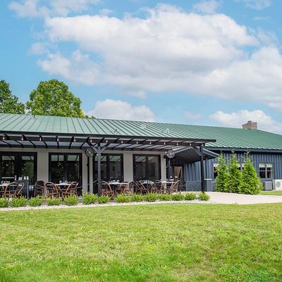 Exterior, building with a patio cover and seating area, greenery and lawn.