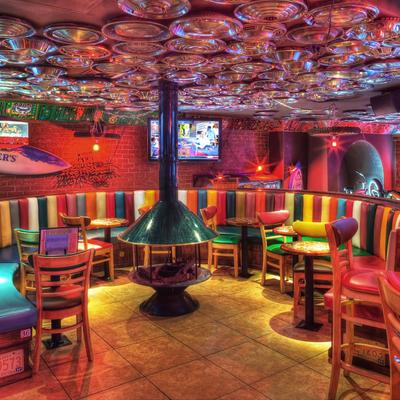 Interior, colorful striped booths, wooden tables, hubcap-covered ceiling, and a central fireplace