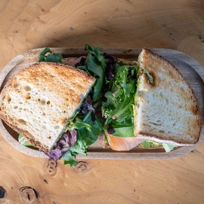 Salmon Avocado Sandwich with greens on a toasted bread, overhead view.
