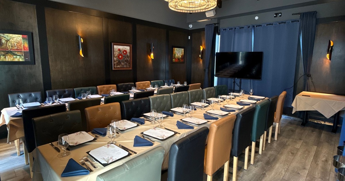 Dining Room Number One at Old Oaks Steakhouse, with banquet tables, a glass chandelier, and a presentation screen.