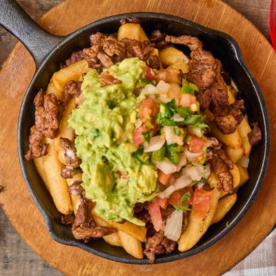 Top-down view of steak fries with guacamole and pico de gallo.