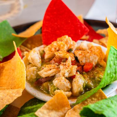 Close-up of shrimp guacamole surrounded by colorful tortilla chips.