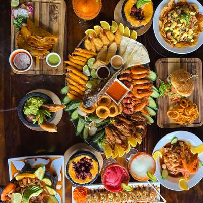 A vibrant spread of Mexican cuisine and cocktails on a wooden table.