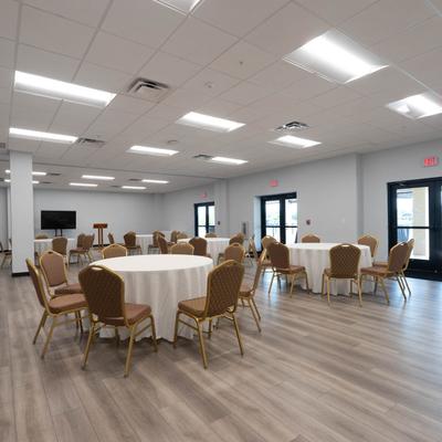 Interior of the community room with round tables, table cloths, and chairs.