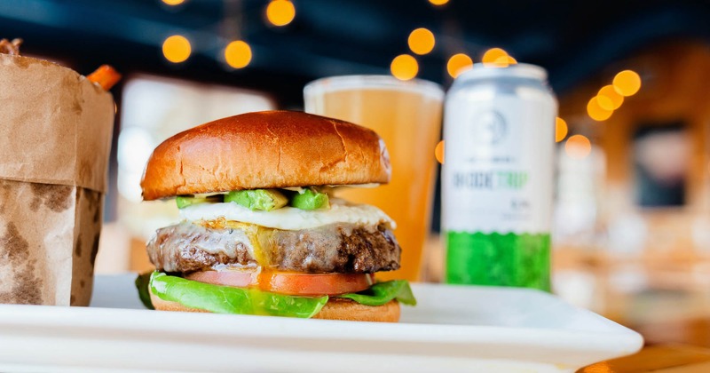 Side view of burger plate with a side dish and beer in the back