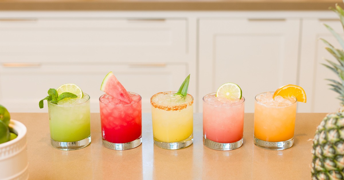 Glasses of refreshing non-alcoholic drinks with fruit garnishes on a table