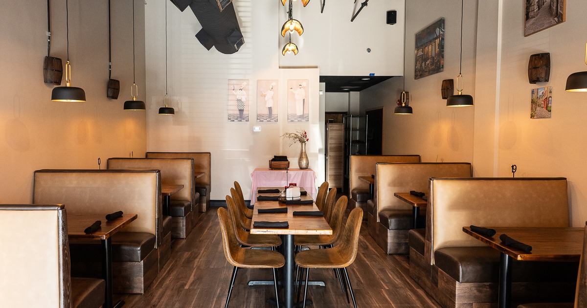 Cozy interior dining area with upholstered booth seats on both sides and a long table in the center