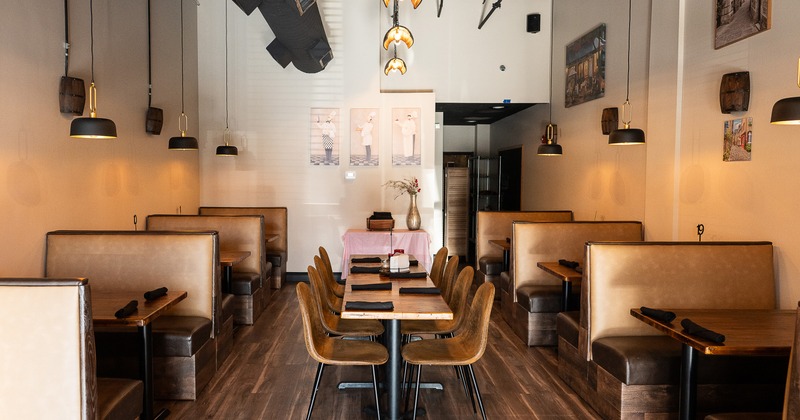 Cozy interior dining area with upholstered booth seats on both sides and a long table in the center