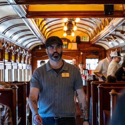A staffer walks down a vintage train aisle between dining booths.