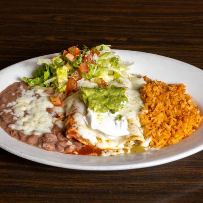 Enchiladas with red and green salsas, sour cream, guacamole, salad, rice, and beans.