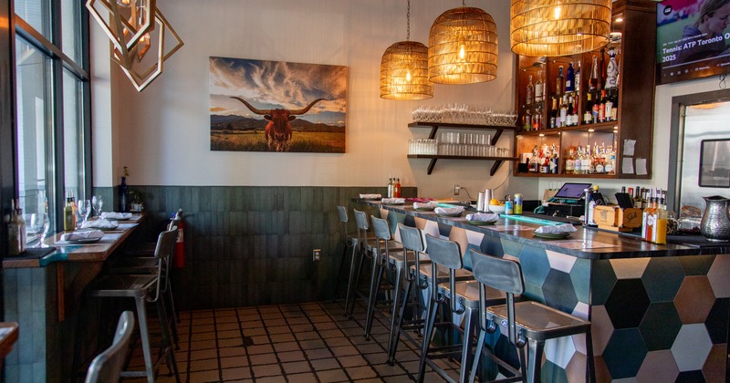 Modern interior, bar area with metal bar stools and a seating area with a counter along the window