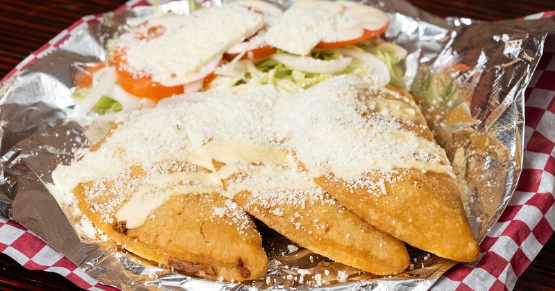 Empanadas topped with crumbled cheese, served with a salad