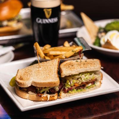 Avocado BLT sandwich on sourdough bread, served with fries and beer.