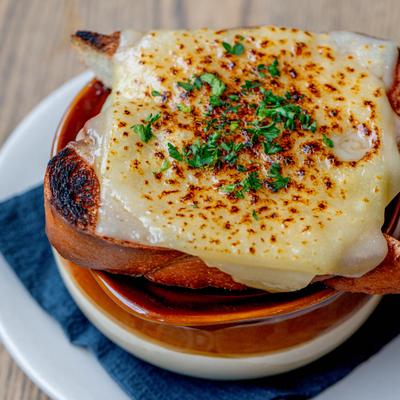A bowl of French Onion Soup topped with toasted bread slice and melted cheese.