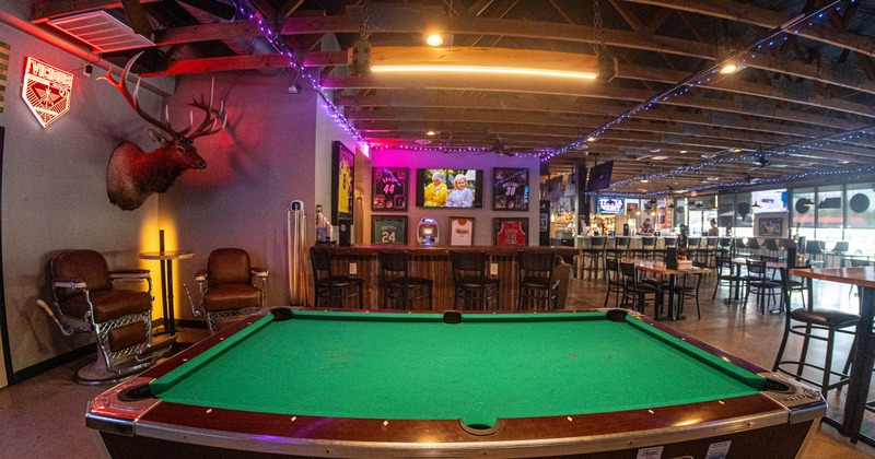 Interior of a bar featuring a pool table, and decorative sports memorabilia