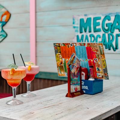 2 margaritas on a table with a menu and table tent