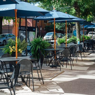 Sidewalk cafe with parasols, parked cars