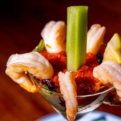 Shrimp cocktail in a glass, with celery and lemon.