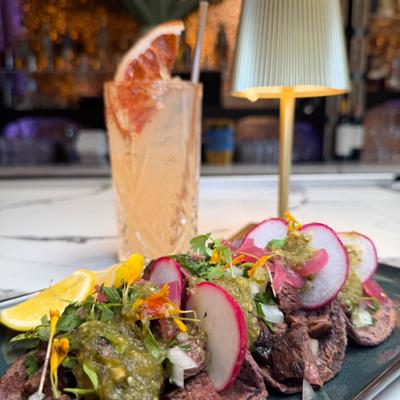 Steak tacos with radishes and green salsa, paired with a grapefruit cocktail.