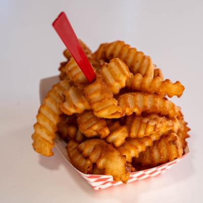 Crinkle-cut French fries served in a red and white checkered paper tray.