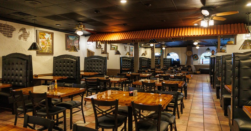 Spacious dining area with booths along the wall on both sides and tables and chairs in the middle