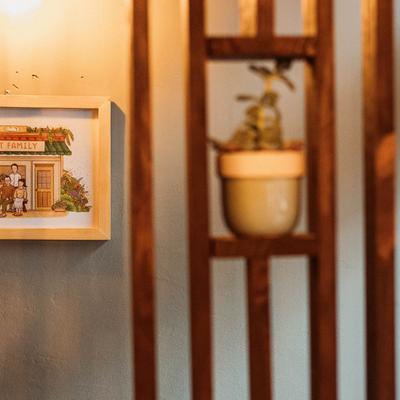 Interior with a framed picture and a plant on a wooden shelf.