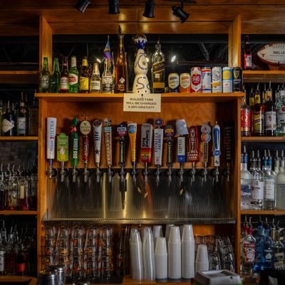 A view of bar shelves with spirits, beer taps, and bar items.
